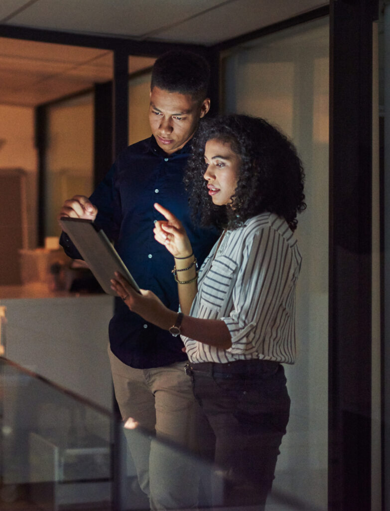 Shot of a young businessman and businesswoman using a digital tablet during a late night at work