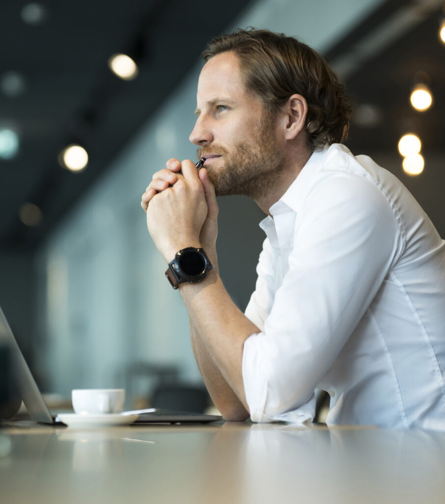 Casual pensative entrepreneur working on laptop in office lounge